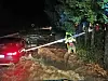 Feuerwehrleute hantieren mit einer Leiter an einem Auto, dass an der zu einem reißenden Strom angeschwollenen Pilach steht.
