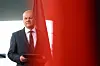 Scholz geht mit einem Umschlag in der Hand zu einem Pressestatement