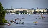 Menschen sind in der Abendsonne mit Stand-Up Boards, Kanus, Ruderbooten und Segelbooten auf der Alster unterwegs.