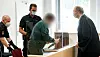 Der 57 Jahre alte Angeklagte (2.v.r.) kommt zu seinem Platz in einem Gerichtssaal im Landgericht.
