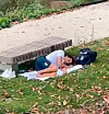 Thomas Ceccon schläft auf einem Handtuch vor einer Parkbank im Olympischen Dorf