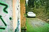Eine verlassene Corvette steht neben dem baufälligen Haus.