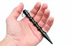 Eine Hand hält einen Kubotan. Ein schwarzer wellenförmiger Stab mit spitzer Spitze.