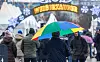 Ein Mann geht im Nieselregen mit seinem Schirm über einen Weihnachtsmarkt.