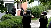 Mit Maschienpistolen im Anschlag nähern sich Polizisten dem Haus.