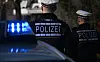 Polizisten stehen an einem Streifenwagen.