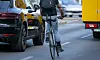 Ein Radfahrer fährt neben einem Auto auf der Straße.