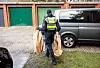 Eine Polizistin mit zwei braunen Säcken, in denen mutmaßliches Beweismittel ist.