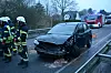 Feuerwehrkräfte stehen vor einem verunfallten Auto.