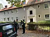 Polizeikräfte und ein Feuerwehrmann vor dem Wohnhaus.