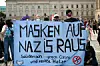 Gegendemonstranten einer Kundgebung gegen die Corona-Maßnahmen sammeln sich und halten ein Banner