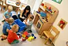 Erzieherin sitzt auf dem Fußboden und spielt mit vier Kindergarten-Kindern