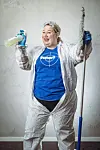 Eine Frau im weißen Anzug mit Reinigungsutensilien