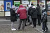 Menschen stehen Schlange, um noch ihr Geld an einem Geldautomaten abzuheben.