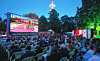 Viele Menschen sitzen im Schanzenpark vor einer großen Kinoleinwand.