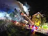Großbrand in Oering: Luftaufnahme eines brennenden Einfamilienhauses, starker Qualm dringt aus dem Dach, davor Feuerwehrwagen, einer mit Drehleiter