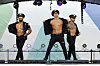Drei Stripper in Polizeiuniformen performen auf einer Bühne.