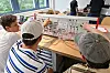 Drei Junge Menschen sitzen an einem Tisch und arbeiten.