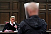 Der Angeklagte steht im Sitzungssaal im Strafjustizgebäude, im Hintergrund sitzt Jessica Koerner, Vorsitzende Richterin am Landgericht.