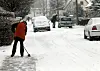 Frau fegt Schnee vom Gehweg