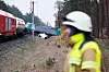 Zwei kollidierte Güterzüge, davor ein Arbeiter