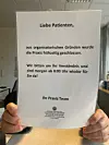 Personalnot: Eine Angestellte in Norderstedt hält einen Zettel hoch, mit dem die Patienten immer öfter über die vorzeitige Schließung der Praxis informiert werden.
