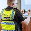 Ein Polizist mit einem Smartphone in der Hand (Symbolfoto)