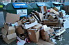 Berge an Kartons stapeln sich vor Altpapier-Containern