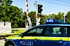 Ein Streifenwagen der Polizei steht vor einem Bahnübergang.