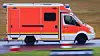 Man sieht einen Krankenwagen auf einer Landstraße fahren.