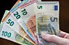 Eine Hand hält mehrere Euro-Scheine wir einen Fächer in die Höhe.