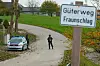 Einsatzkräfte der Polizei stehen in Altenfelden im Mühlviertel in Oberösterreich, nachdem ein Mann erschossen worden ist. Im Vordergrund ist ein Straßenschild, im Hintergrund stehen die Beamten mit ihrem Wagen an einer Wiese.
