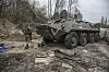 Ein ukrainischer Soldat geht an einem Schützenpanzer russischer Streitkräfte vorbei auf einer Straße in der Nähe von Tschernobyl.
