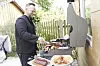Mann steht am Grill und wendet Fleisch.