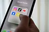 Eine Frau hält ein Smartphone, auf dessen Display verschiedene Social Media Apps angezeigt werden