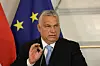 Man sieht Viktor Orban bei einer Rede. Er trägt einen schwarzen Anzug, weißes Hemd und hellblaue Krawatte, hinter ihm ist die Europäische Flagge zu sehen.