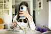 Junge Frau mit Teller und Smartphone