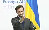 Mann im Anzug vor einer ukrainischen Flagge