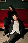 Nick & June sitzen auf einem roten Sofa