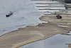 Ein Binnenschiff fährt bei Niedrigwasser an freiliegenden Felsen und Sandbänken auf dem Rhein bei Bacharach.
