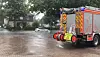 Ein Auto fährt auf einer überflutete Straße.