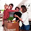 Eine Familie packt eine Box von Frischepost aus