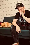 Oliver Pfeiffer alias Jonathan Johnson in seinem Geschäft auf der Couch. Neben ihm liegt sein Hund „Wippo“