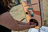 Sonnencreme-Spender am Strand, Frau hält Hände unter den Sensor.