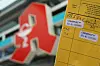 Ein Impfpass wird vor einer Apotheke in die Kamera gehalten (Symbolfoto)