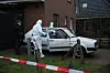 Ermittler der Mordkommission sichern Spuren an einem Fahrzeug vor dem Haus.