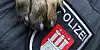 Ein Polizeihund legt seine Pfote auf das Abzeichen an einer Polizei-Uniform.