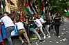 Pro-Palästina-Demonstranten versuchen eine Absperrung zu durchbrechen. Die baskische Polizei und Mitarbeiter der Radsport-Teams versuchen, dies zu verhindern.