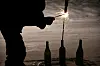 Eine Person zündet an Silvester eine Rakete an, die in einer Flasche steht.