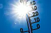 Thermometer mit greller Sonne im Hintergrund